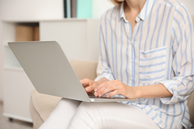 Young woman with laptop sitting indoors, closeup