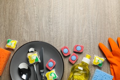 Photo of Flat lay composition with dishwasher detergent pods and tablets on wooden table, space for text