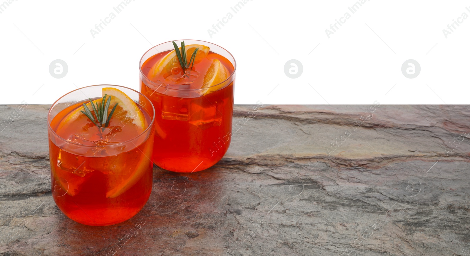 Photo of Aperol spritz cocktail, orange slices and rosemary in glasses on grey textured table against white background