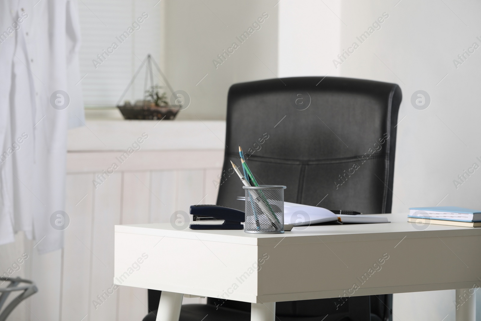 Photo of Modern workplace with white desk and comfortable office chair in room