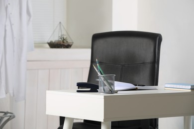 Photo of Modern workplace with white desk and comfortable office chair in room