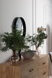 Photo of Eucalyptus branches near vessel sink on bathroom vanity. Interior design