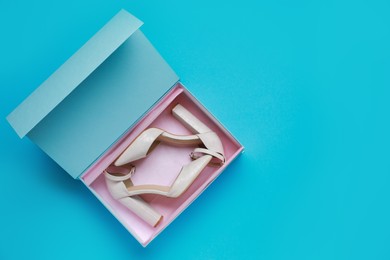 Photo of Stylish women's shoes in cardboard box on light blue background, top view. Space for text
