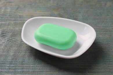 Photo of Dish with soap bar on green wooden table