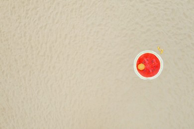 Image of Round watermelon beach towel, ball and flip flops on sand, aerial view. Space for text