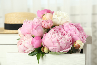 Photo of Bouquet of beautiful peonies in commode drawer indoors
