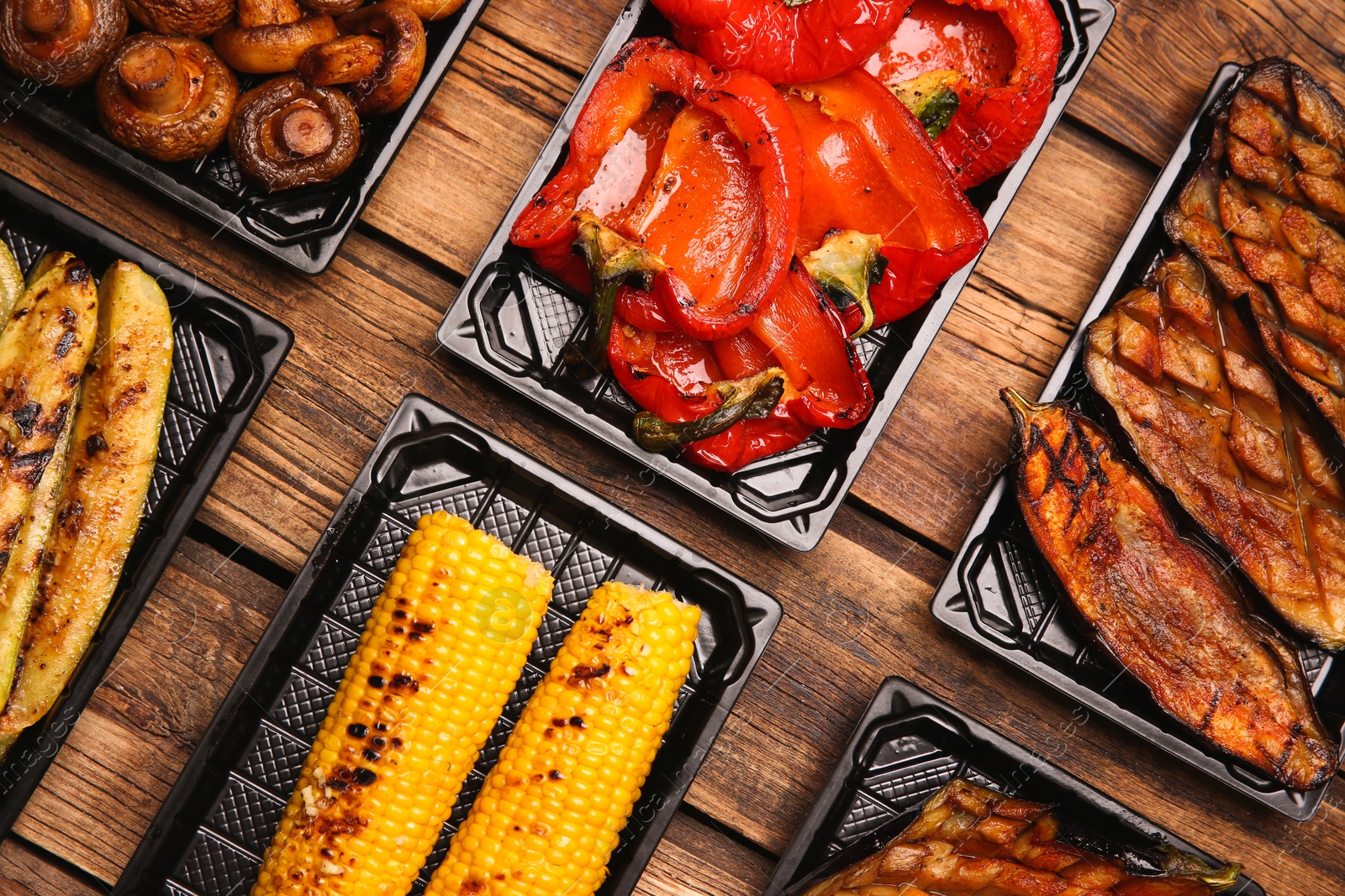 Photo of Plastic containers with different grilled meal on wooden table, flat lay. Food delivery service