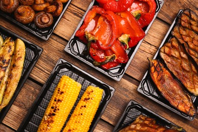 Photo of Plastic containers with different grilled meal on wooden table, flat lay. Food delivery service