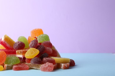 Photo of Pile of delicious bright jelly candies on violet background. Space for text