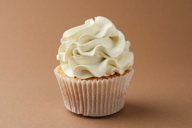 Photo of Tasty vanilla cupcake with cream on dark beige background, closeup