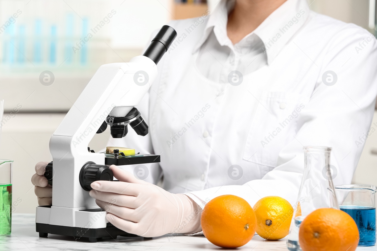 Photo of Scientist inspecting slice of apple with microscope in laboratory, closeup. Poison detection