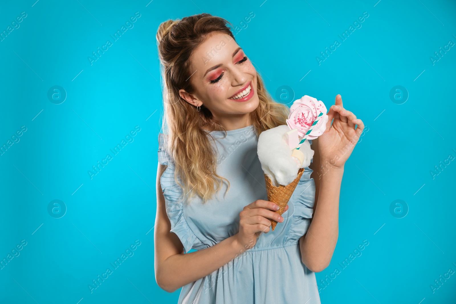 Photo of Portrait of young woman holding cotton candy dessert on blue background