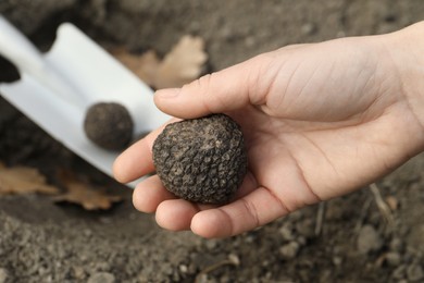 Woman holding fresh truffle in hand outdoors, closeup