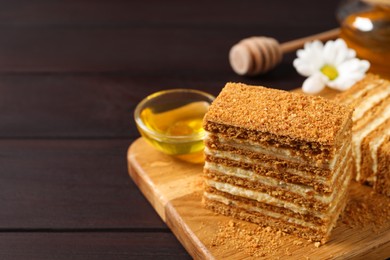 Photo of Delicious layered honey cake served on wooden table. Space for text