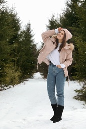 Young woman in snowy conifer forest. Winter vacation