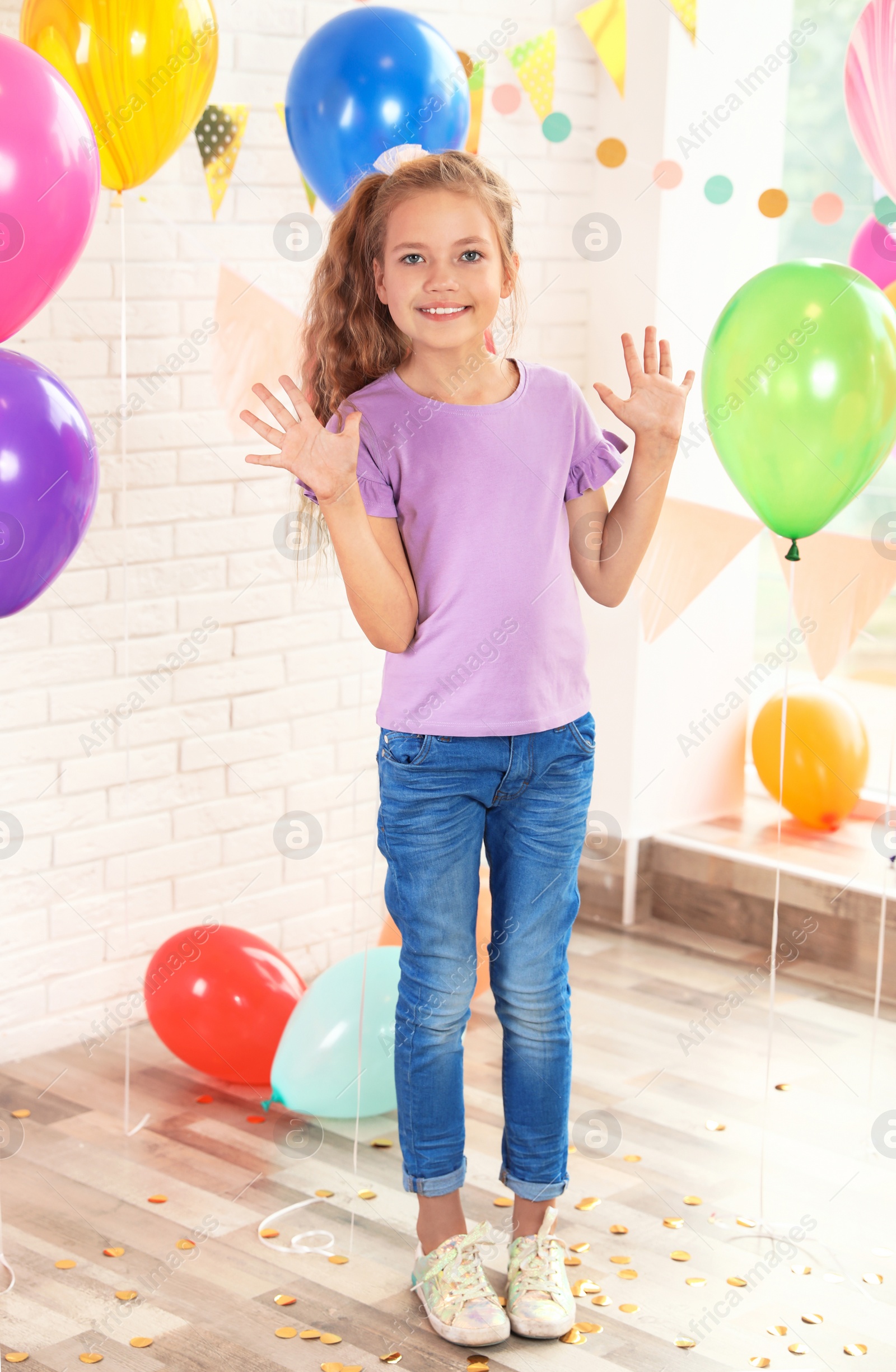 Photo of Happy girl near bright balloons at birthday party indoors