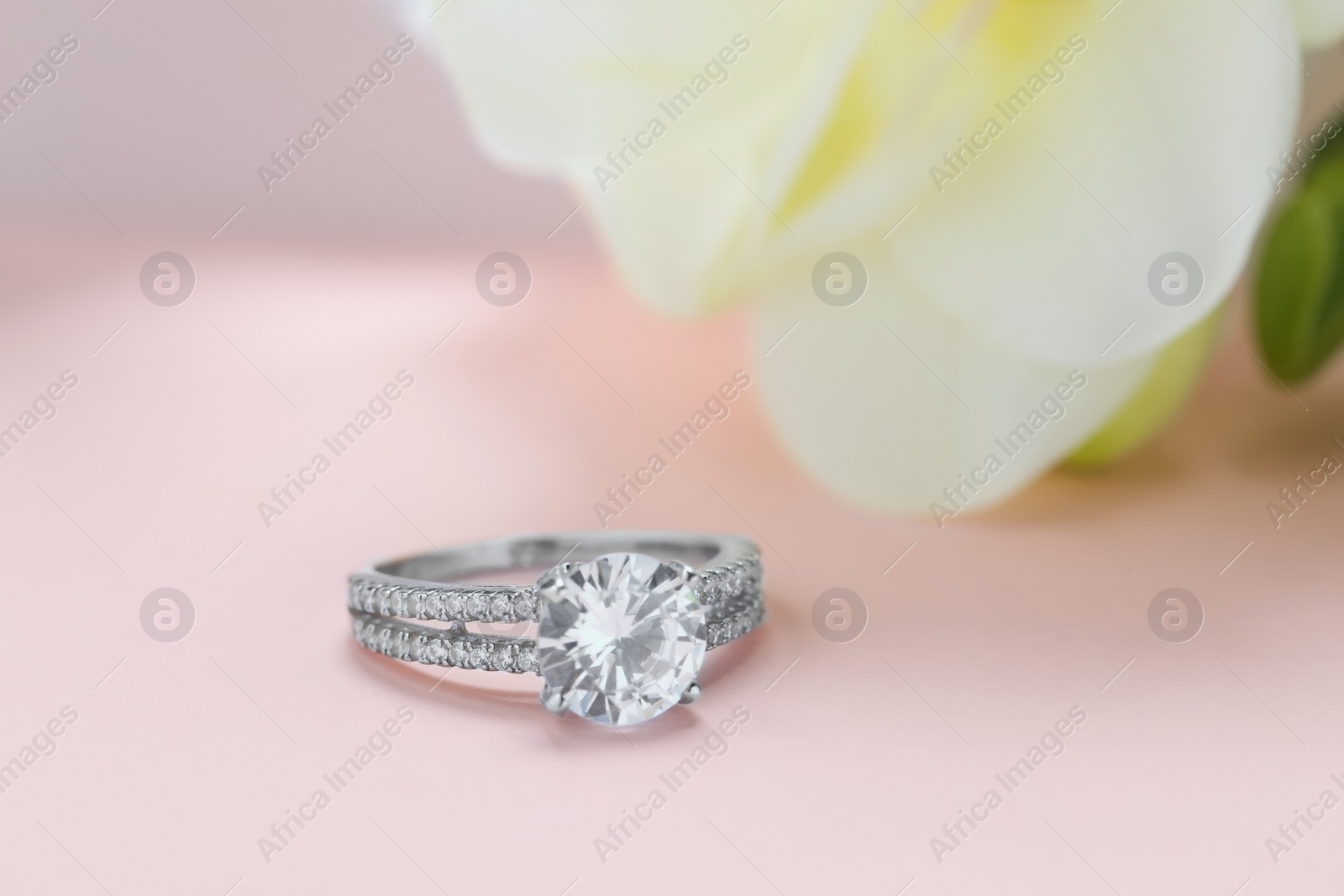 Photo of Beautiful ring with gemstones on pale pink background. Luxury jewelry