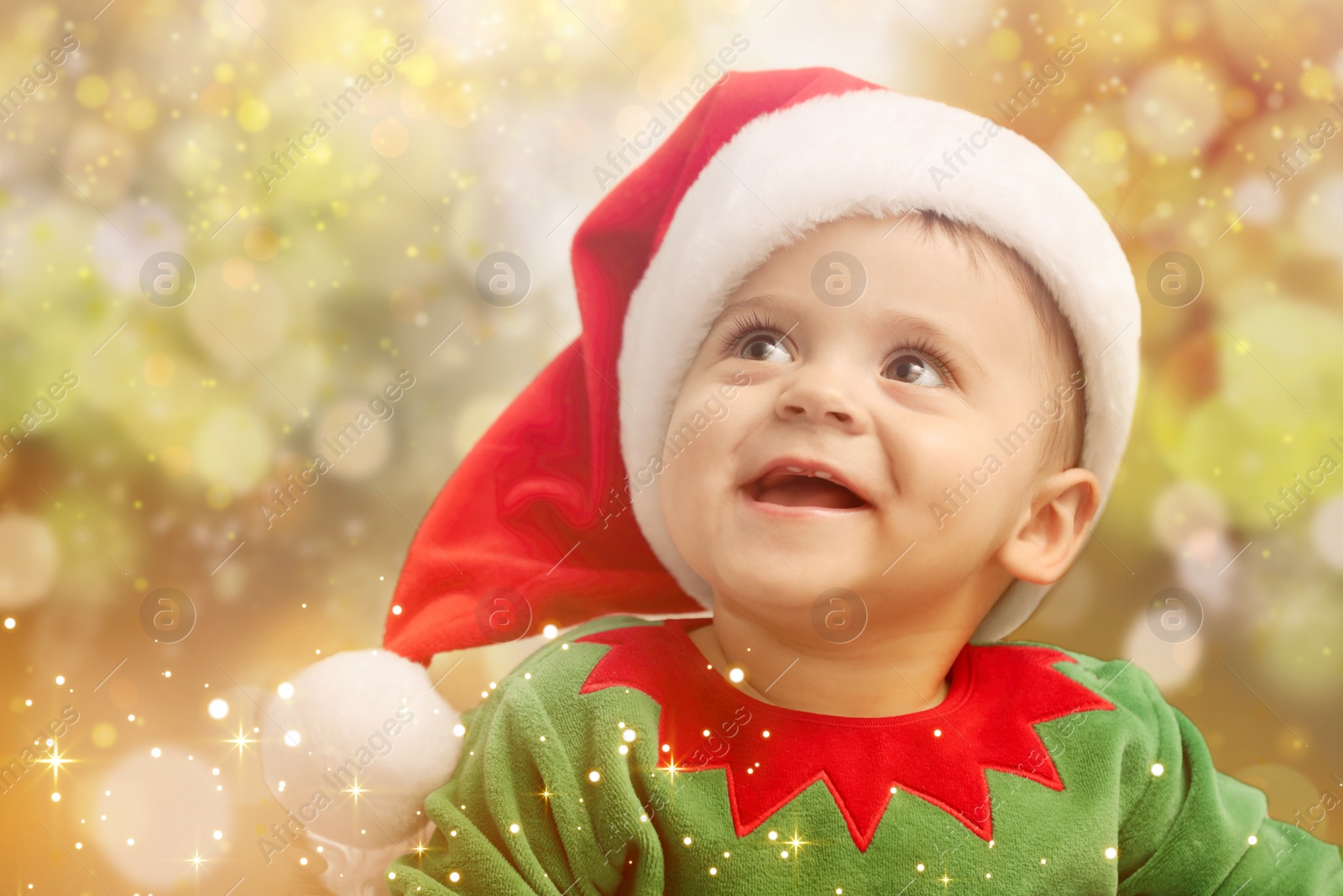 Image of Cute baby in Christmas costume against blurred lights. Magical festive atmosphere