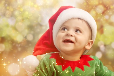 Image of Cute baby in Christmas costume against blurred lights. Magical festive atmosphere