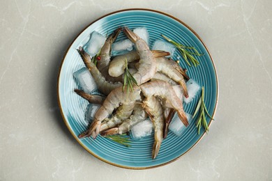 Photo of Fresh raw shrimps with rosemary and ice cubes on light grey marble table, top view