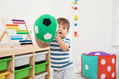 Photo of Little child playing with soft ball in room
