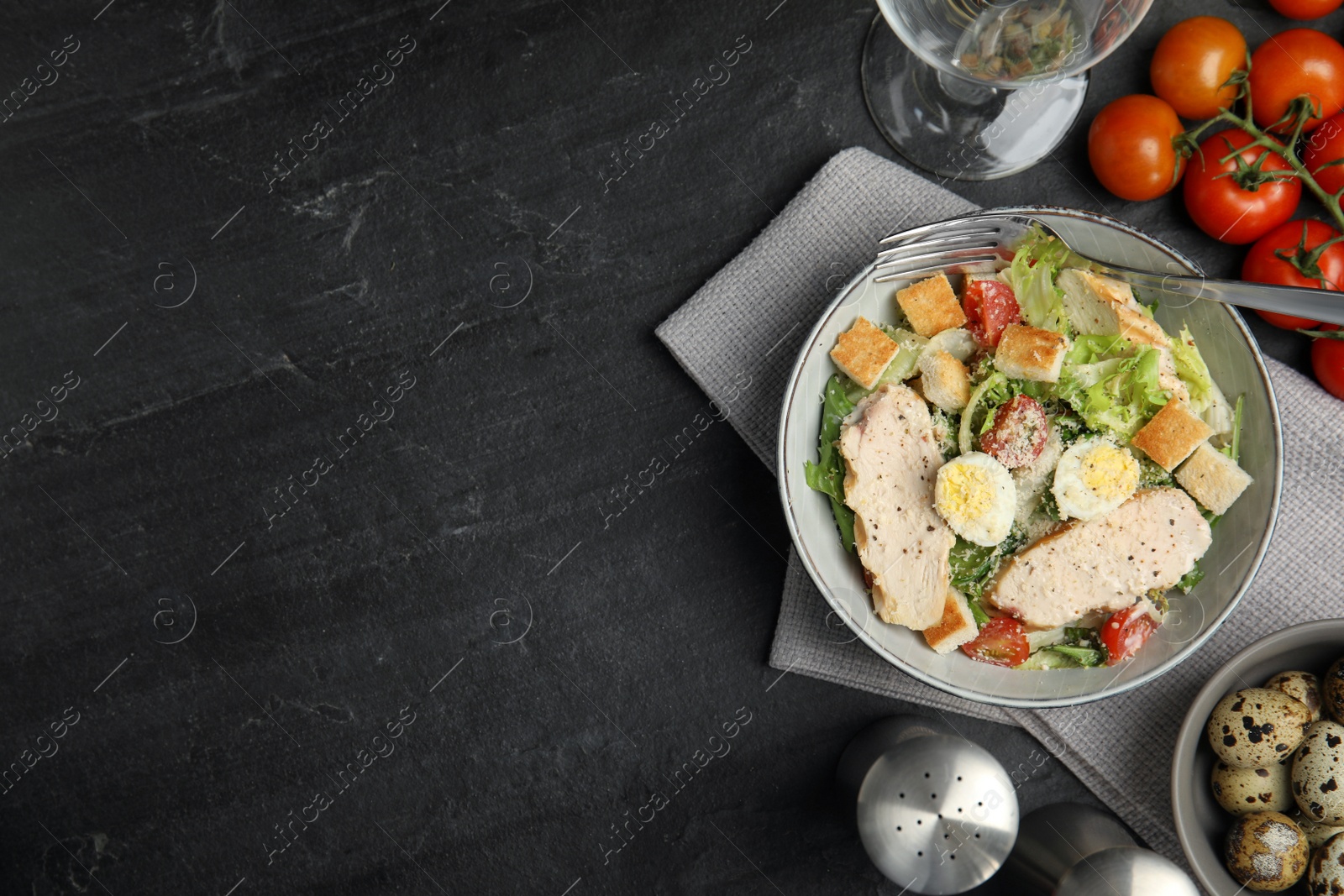 Photo of Delicious Caesar salad in bowl on black table, flat lay. Space for text