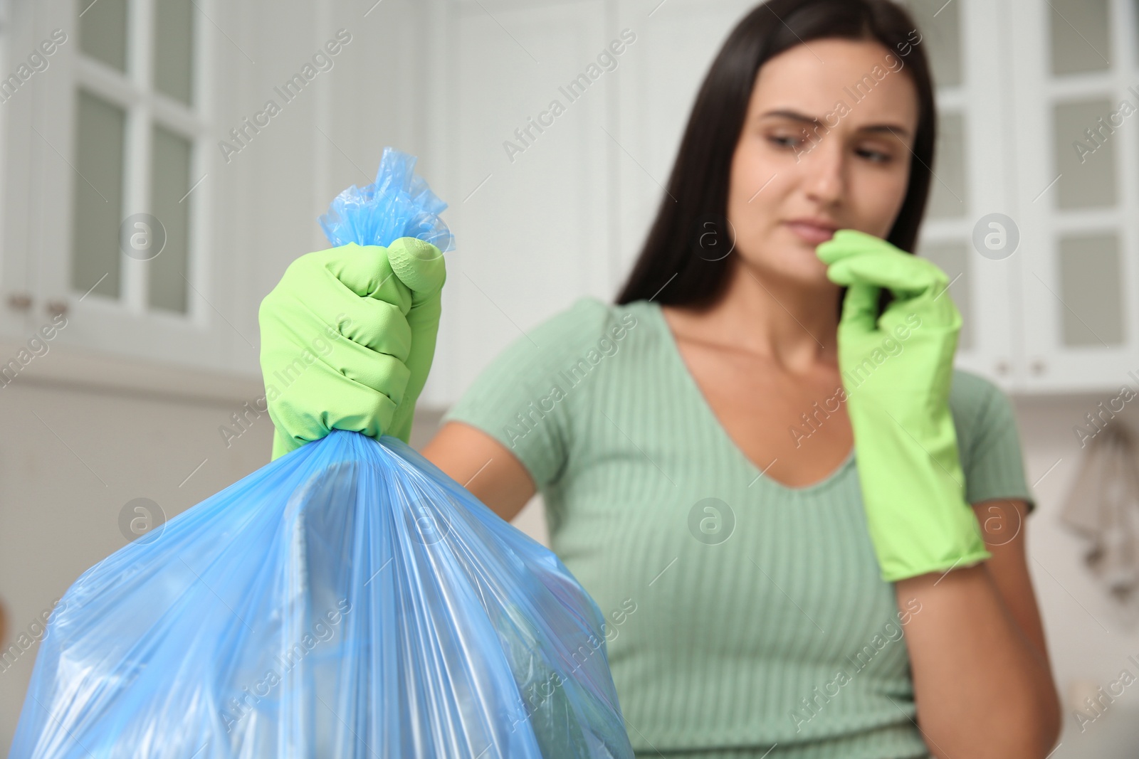 Photo of Woman holding full garbage bag at home, focus on hand