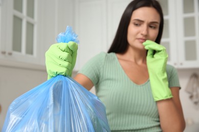 Woman holding full garbage bag at home, focus on hand