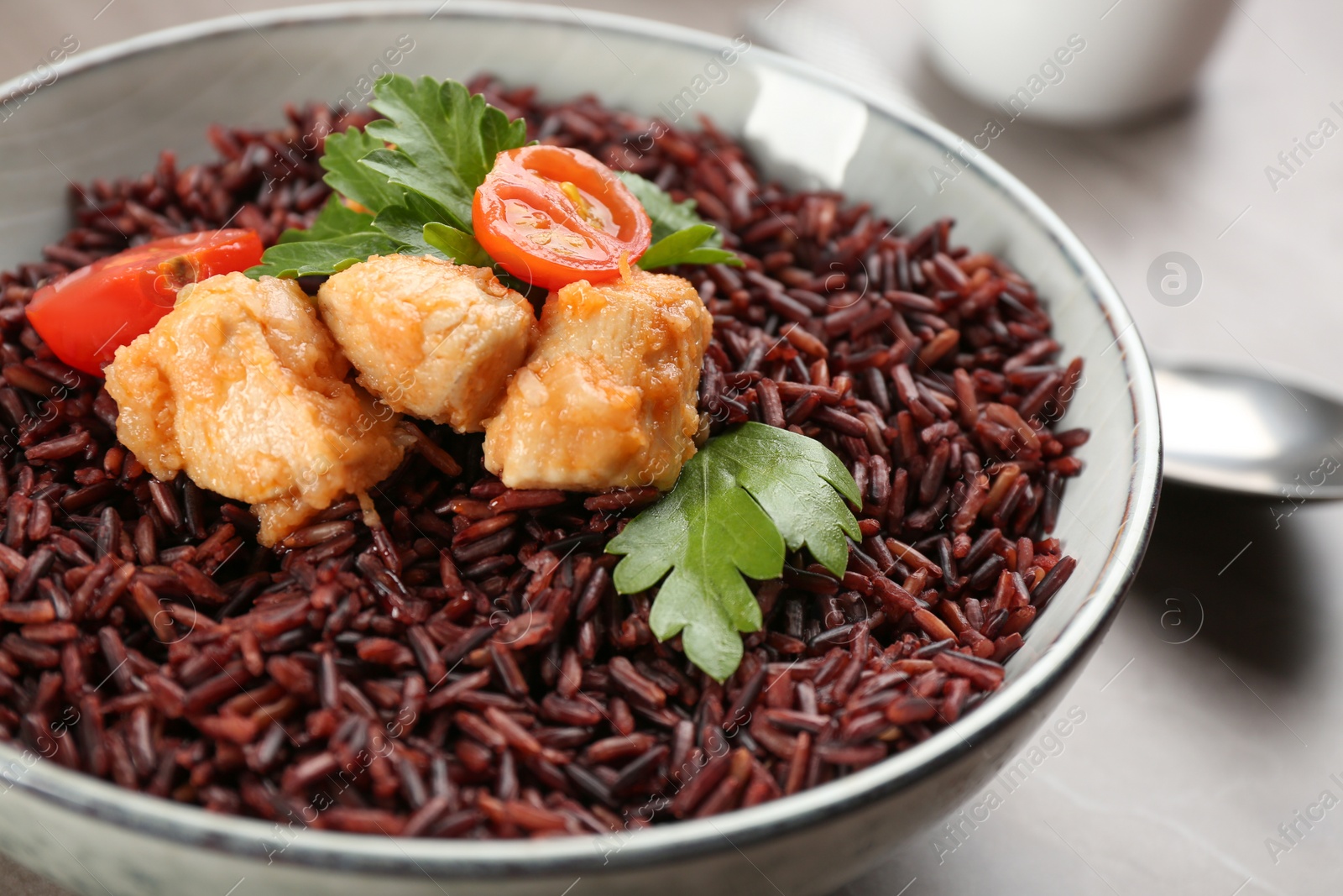 Photo of Tasty brown rice with chicken on table, closeup