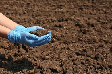 Photo of Woman holding pile of soil outdoors, closeup. Space for text