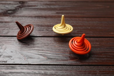 Three bright spinning tops on wooden table