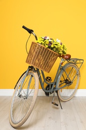 Retro bicycle with wicker basket near color wall