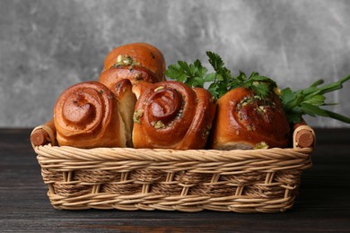 Photo of Delicious pampushky (buns with garlic) in wicker basket on wooden table