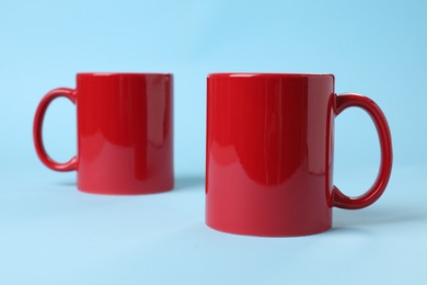 Two red ceramic mugs on light blue background