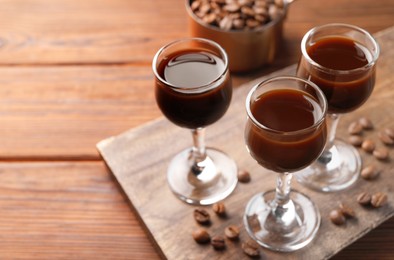 Photo of Shot glasses with coffee liqueur and beans on wooden table, closeup. Space for text