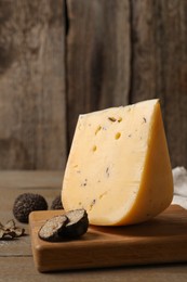 Photo of Delicious cheese and fresh black truffles on wooden table