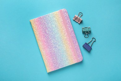 Photo of New stylish planner and paper clips on light blue background, flat lay