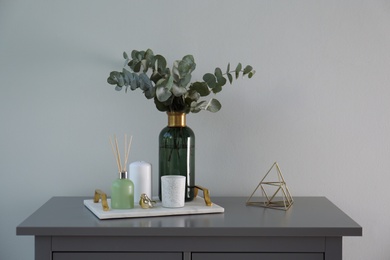 Composition with eucalyptus branches in vase on chest of drawers indoors. Interior design