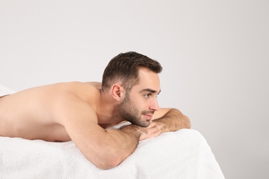 Photo of Handsome man relaxing on massage table against white background. Spa service