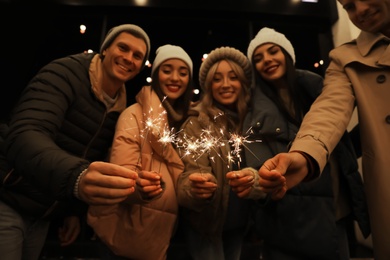 Photo of Group of people holding burning sparklers, focus on hands