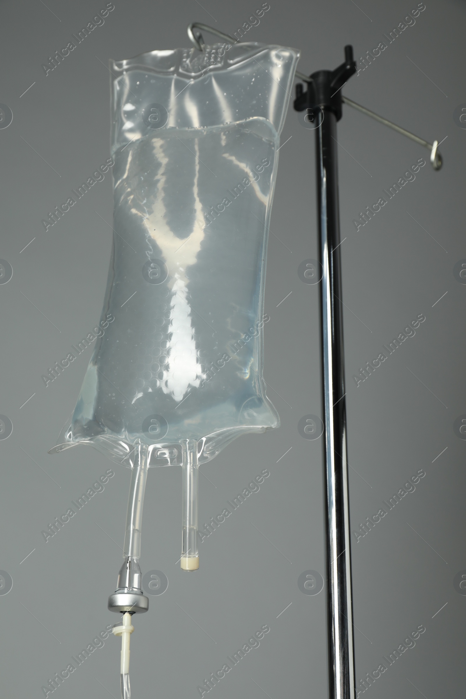 Photo of IV infusion set on pole against grey background, closeup