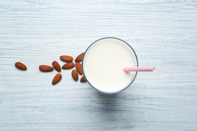 Glass of milk and nuts on wooden background, top view