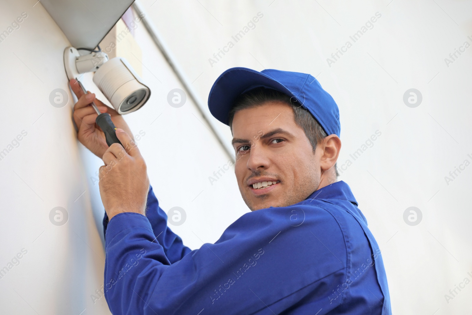 Photo of Technician installing CCTV camera on wall outdoors