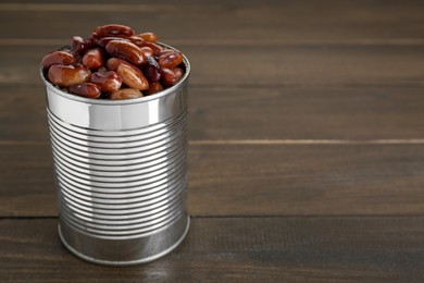 Photo of Tin can with kidney beans on wooden table, space for text