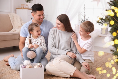 Photo of Happy family with box of Christmas ornaments at home