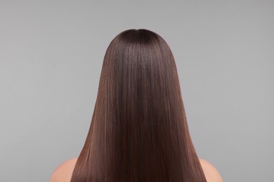 Woman with smooth healthy hair after treatment on light grey background, back view