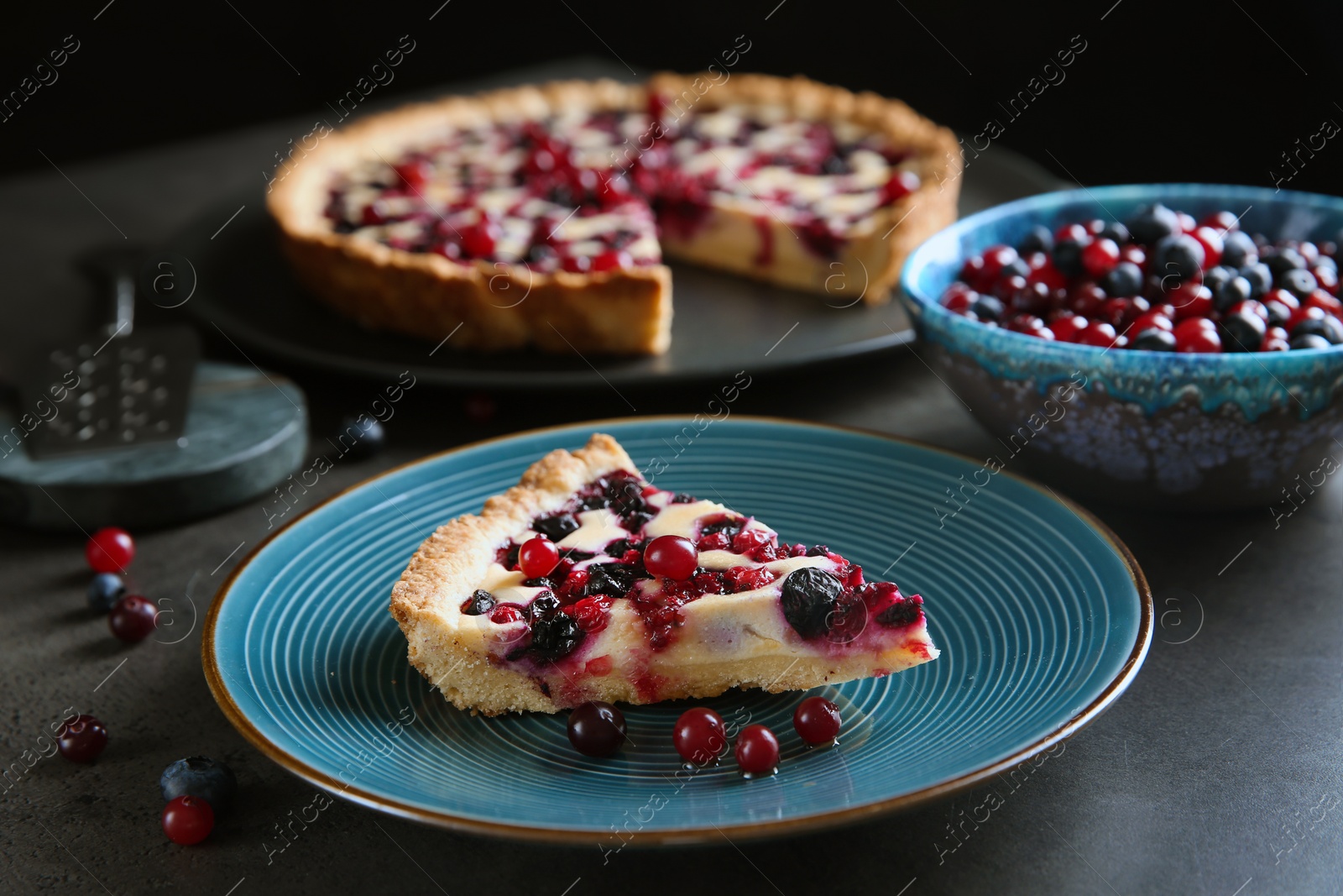 Photo of Piece of delicious currant pie and fresh berries on grey table