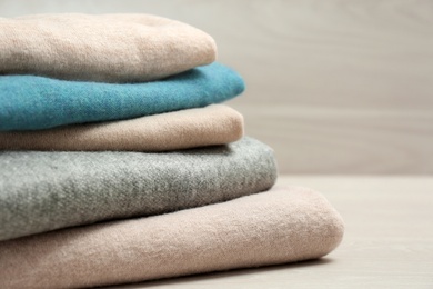 Stack of cashmere clothes on wooden table, closeup