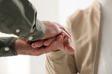 Photo of Trust and support. Men joining hands on blurred background, closeup