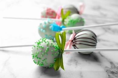 Different tasty cake pops on white marble background